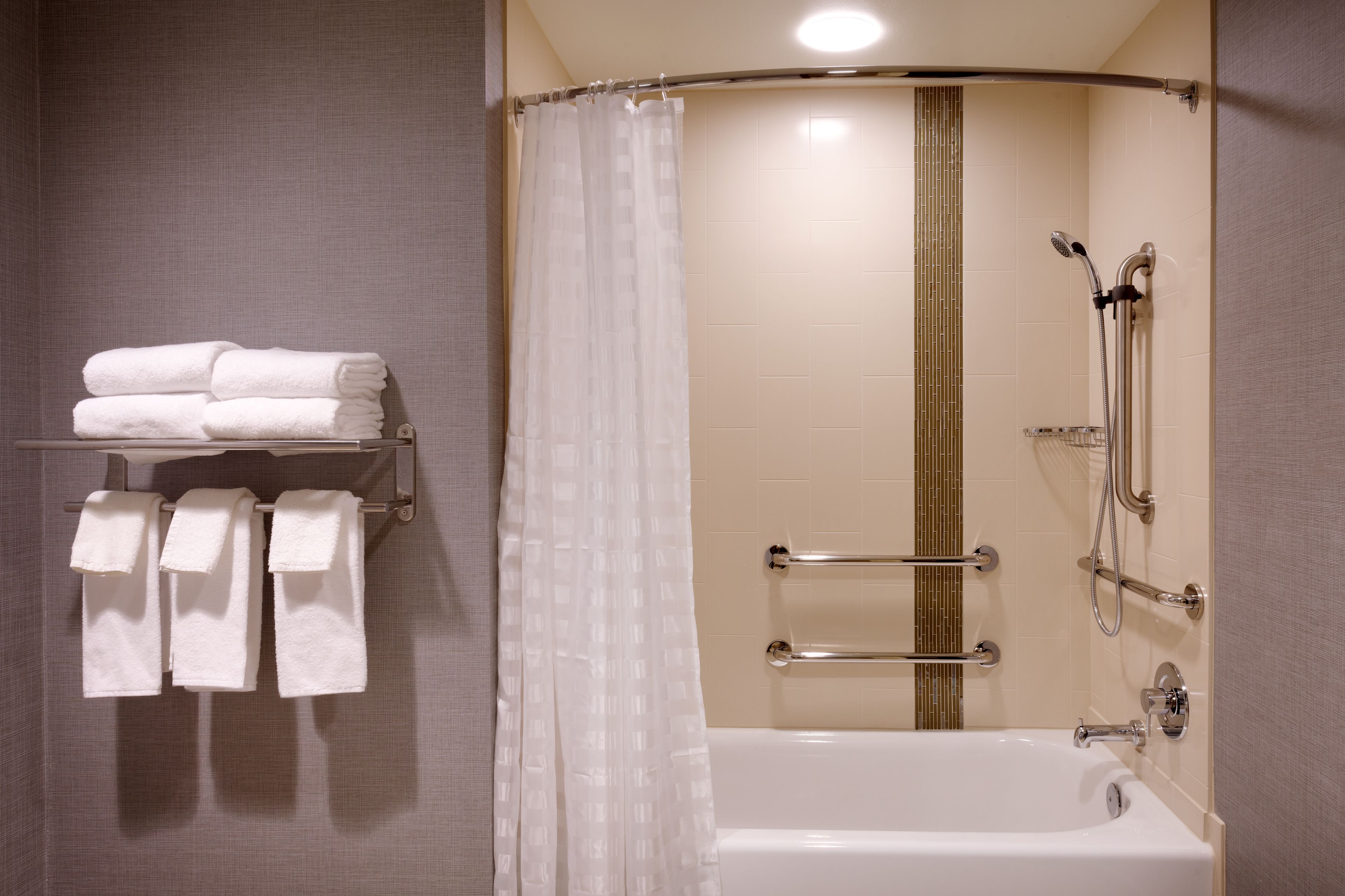 A modern bathroom with a bathtub, shower, and towel rack.