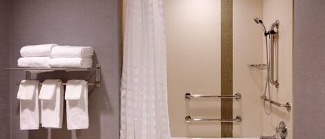 A modern bathroom with a bathtub, shower, and towel rack.