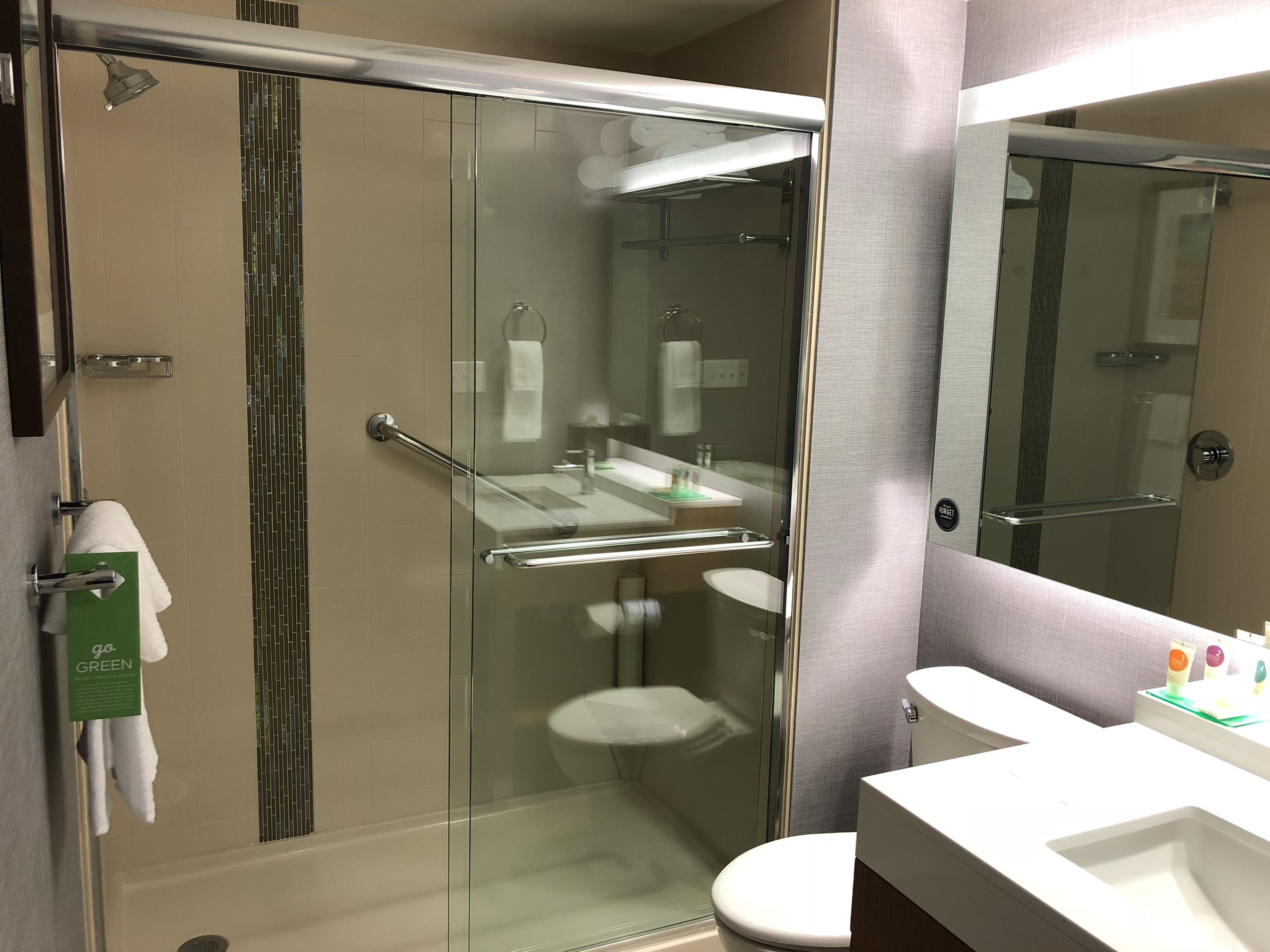 Un baño moderno con cabina de ducha de vidrio, inodoro blanco y tocador con espejo.