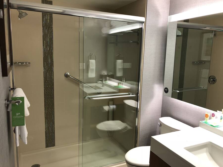 Un baño moderno con cabina de ducha de vidrio, inodoro blanco y tocador con espejo.