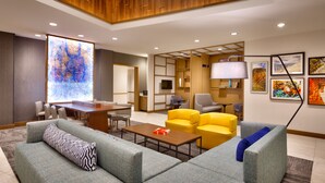 Een moderne hotellobby met een grote kaart aan de muur, comfortabele zitplaatsen, een televisie en kunstwerken.