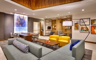 Un moderno vestíbulo de hotel con un mapa grande en la pared, asientos cómodos, un televisor y obras de arte.