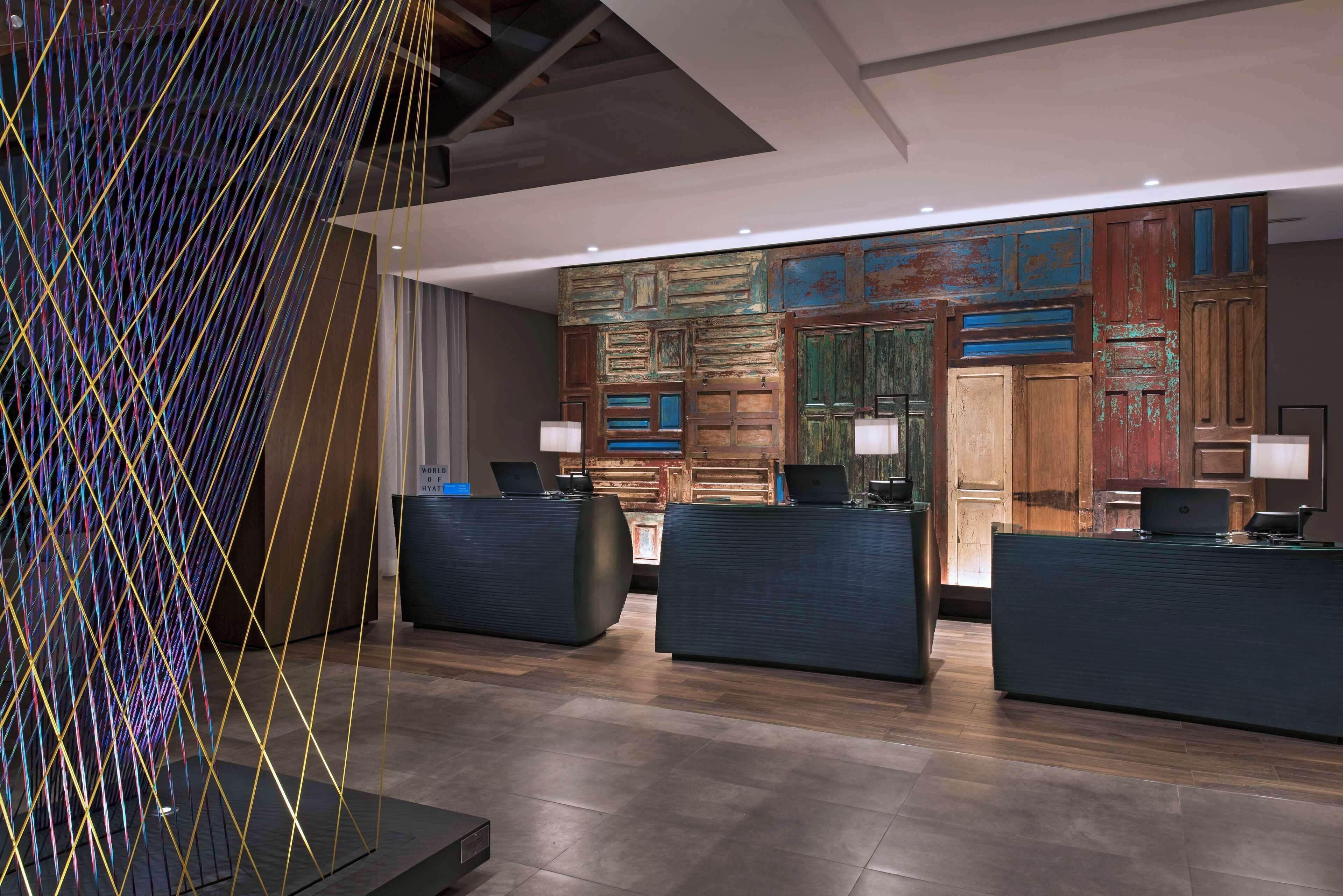 A modern reception area with three dark reception desks, a colorful abstract wall art, and a wooden panel wall with a rustic finish.