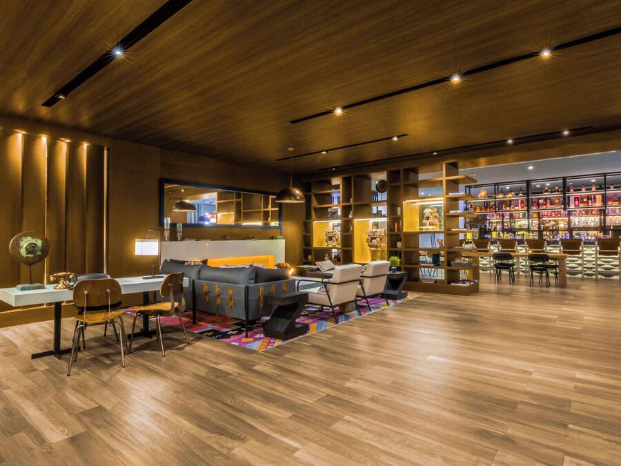 A modern lounge area with a sofa, chairs, a coffee table, and a bar area with shelves.
