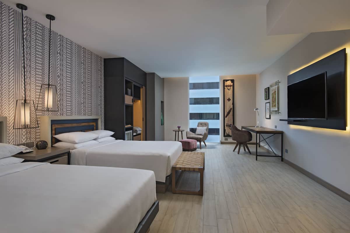 Une chambre d’hôtel moderne avec deux lits, un bureau, une chaise, une télévision et une grande fenêtre.