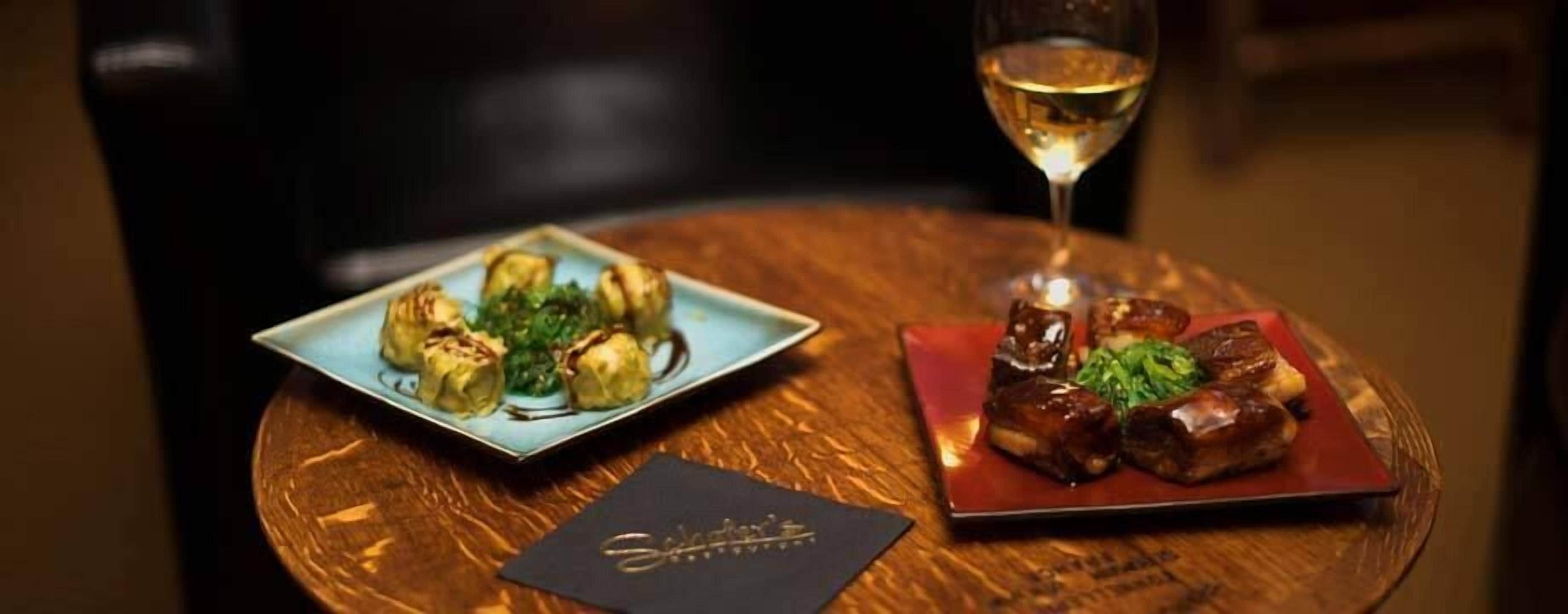 A table with two plates of food and a glass of white wine.