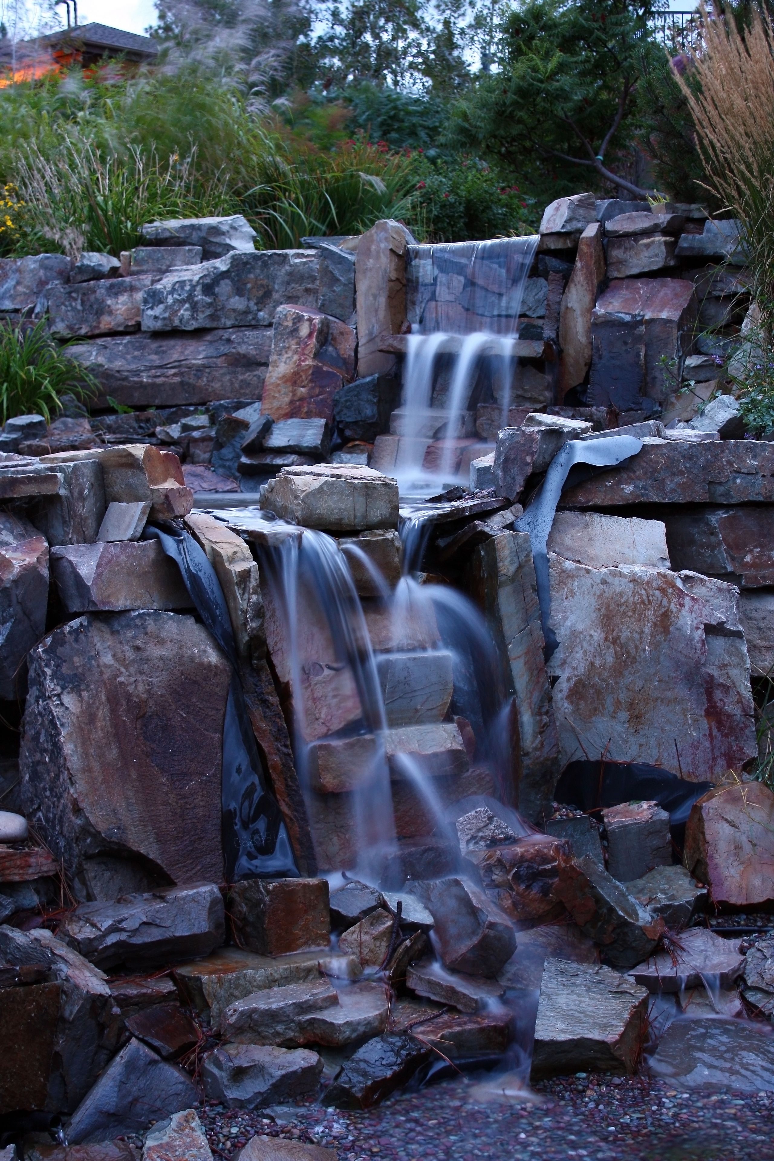 A waterfall cascading over a rocky terrain with a natural backdrop of trees and plants.