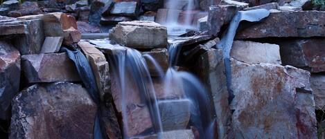 A waterfall cascading over a rocky terrain with a natural backdrop of trees and plants.