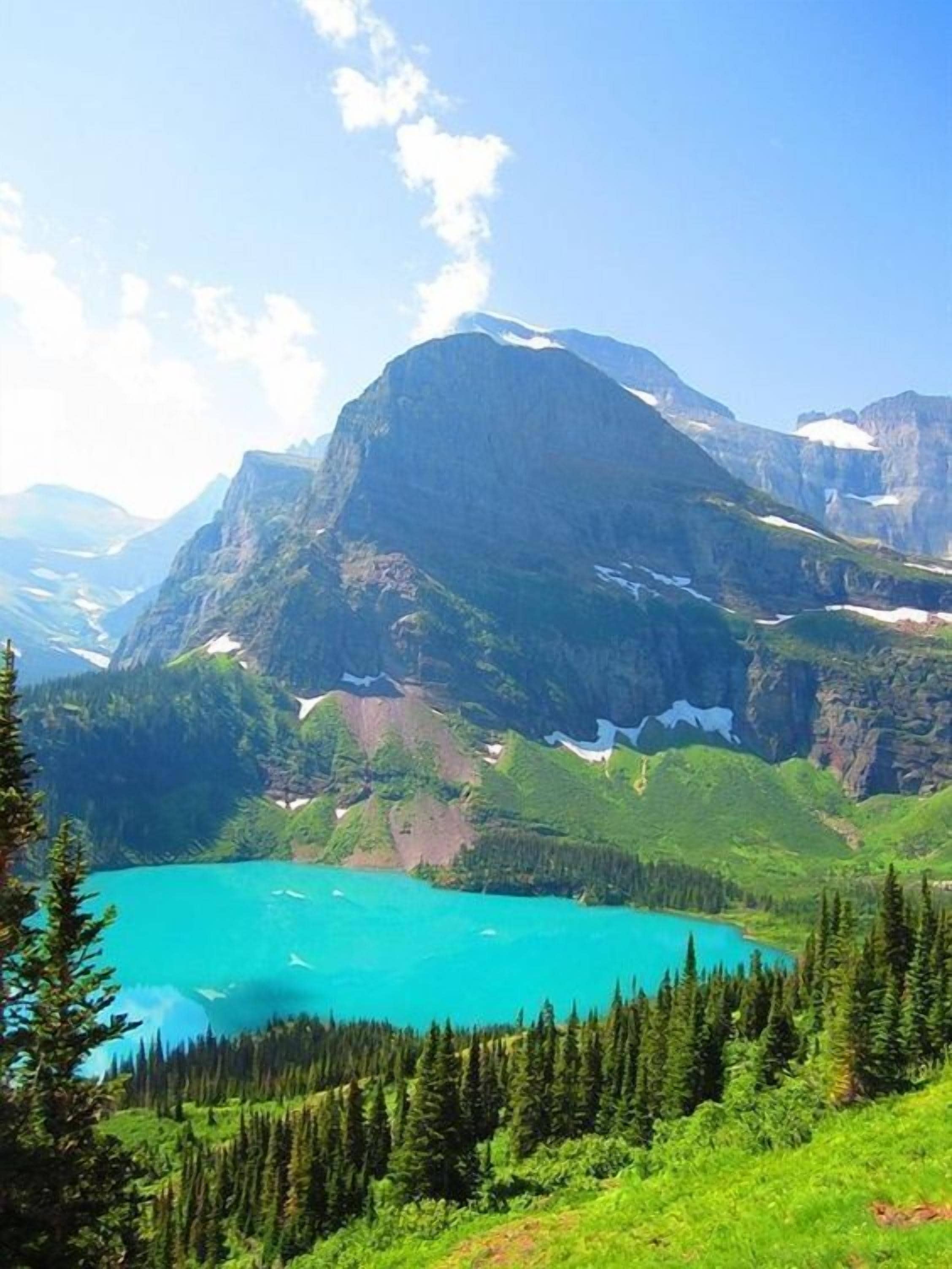 Paisaje montañoso con un lago turquesa rodeado de densos bosques.