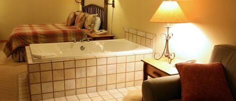 A hotel room with a large bathtub, two beds, a sofa, and a lamp.