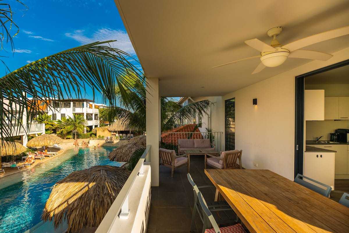 Ein Balkon mit Pool, Essbereich und Küche.