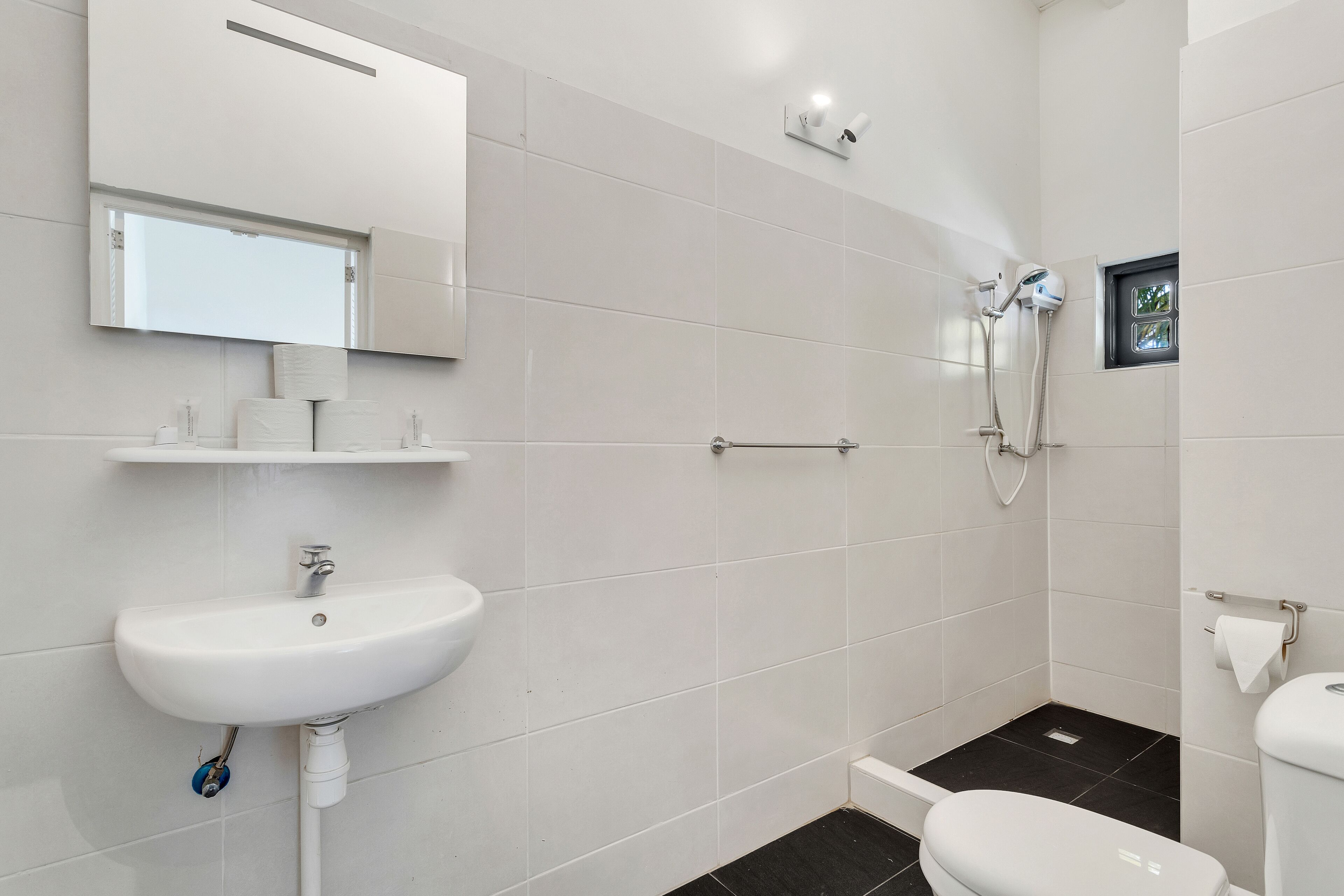 Une salle de bain moderne avec un lavabo blanc, un miroir et une douche.