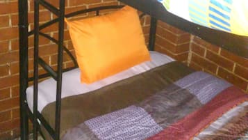 Un lit superposé avec une couvre-lit colorée et deux oreillers orange.