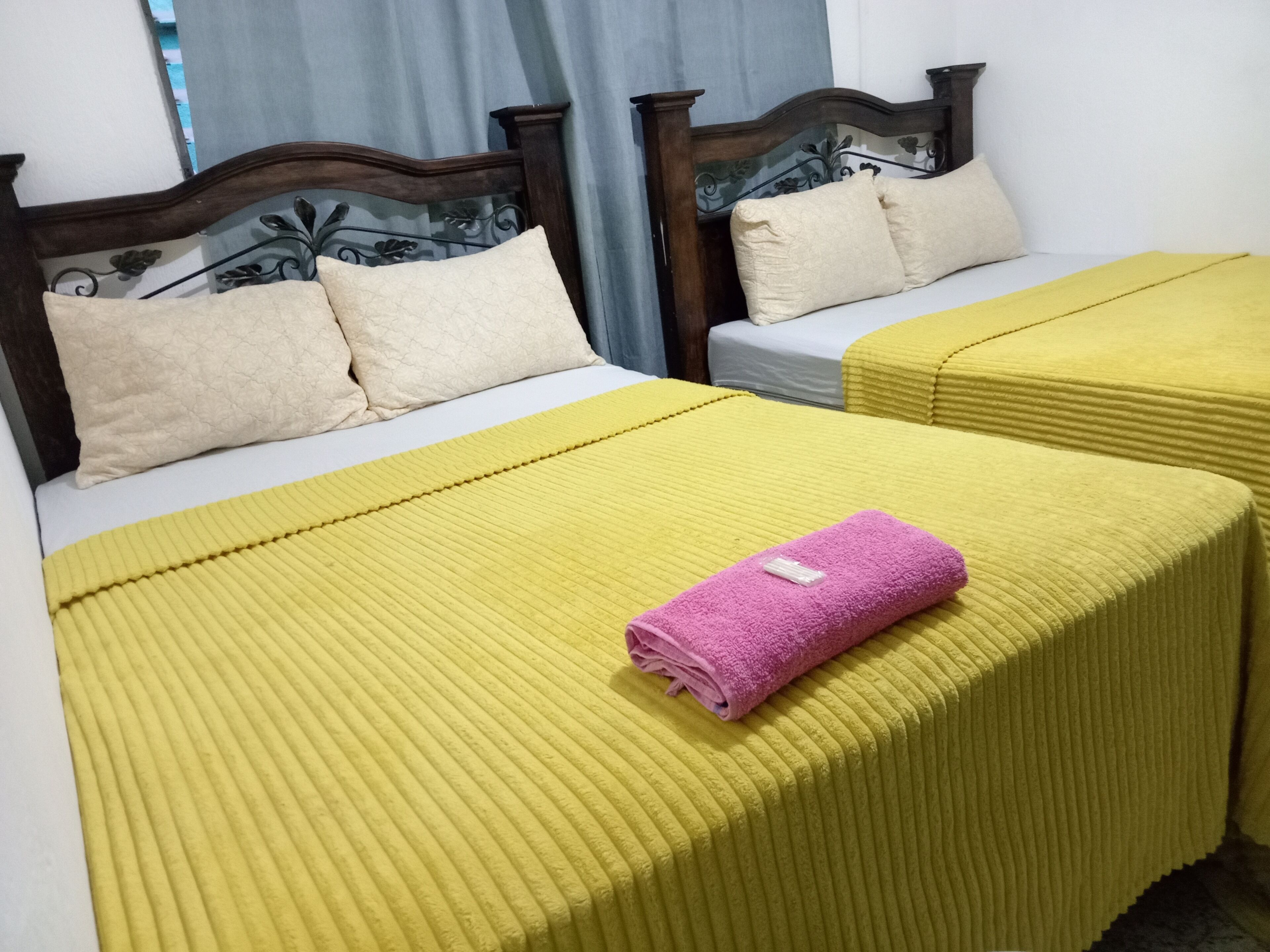 A hotel room with two beds, each with a headboard and pillows.