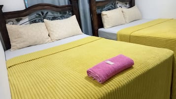 A hotel room with two beds, each with a headboard and pillows.