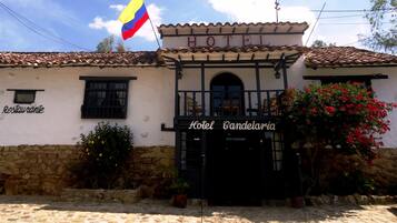 A building with a sign reading "Hotel Candelaia" and a flag above it.