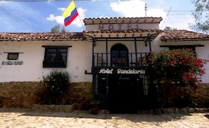 A building with a sign reading "Hotel Candelaia" and a flag above it. - Hotel La Candelaria Real (Villa de Leyva)