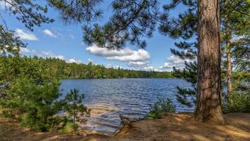 A natural landscape with a lake, trees, and a clear sky.