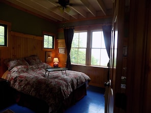 Relax in a serene bedroom with a large bed, wooden paneling, and a bedside table.