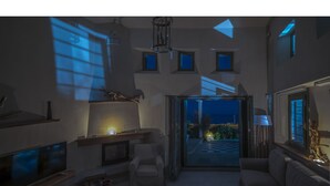 Una sala de estar moderna con chimenea, televisión y vistas al exterior.