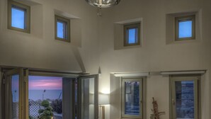 Una habitación con vista al atardecer, una lámpara en el techo, una ventana con vistas y una planta pequeña en el alféizar.