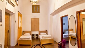 Une chambre d’hôtel avec deux lits, un plafond en bois, un lustre, un miroir et une petite table à manger.