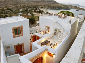 Eine Dachterrasse mit Sitzgelegenheiten im Freien und Blick aufs Meer.