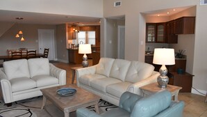 A living room with two white leather sofas, a coffee table, and a blue armchair. There are two lamps on side tables. - New Orleans Area Waterfront Retreat 117 Near the French Quarter/ Bourbon Street (Slidell)