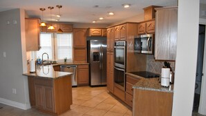 A kitchen with wooden cabinets, stainless steel appliances, and a granite countertop. - New Orleans Area Waterfront Retreat 117 Near the French Quarter/ Bourbon Street (Slidell)