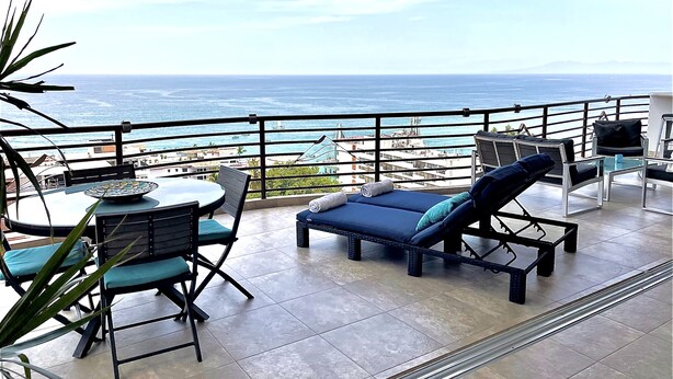 A balcony with a table and chairs, a lounge chair, and a view of the ocean. - Signature 406 Private Pool Sept 18-23 @ -50%, Oct 18-23 @ -40%, Nov 18-22 @ -25% (Puerto Vallarta,)