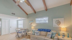 Ein Wohnzimmer mit einem beigefarbenen Sofa, einem Couchtisch und einem Essbereich mit Tisch und Stühlen.