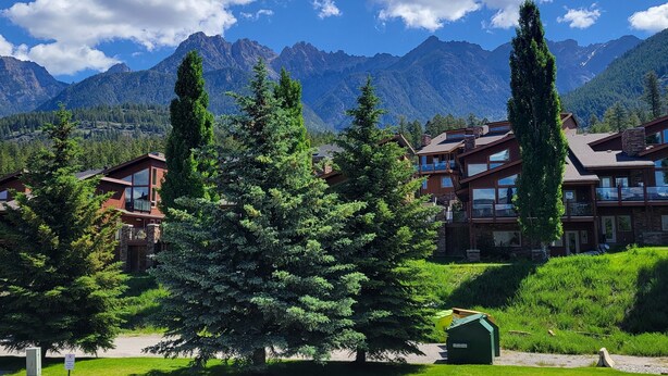 A mountain lodge with multiple floors, large windows, and a view of the surrounding mountains. - Fairmont Hot Springs Get-A-Way - Escape with Ease (Fairmont Hot Springs)
