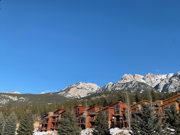 A mountain lodge with multiple wooden buildings, surrounded by snow-covered mountains and evergreen trees. - Fairmont Hot Springs Get-A-Way - Escape with Ease (Fairmont Hot Springs)