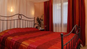 Una camera da letto con un letto, tende e un comodino con un vaso.