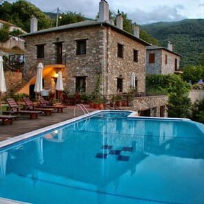A stone building with a swimming pool, outdoor seating, and a view of the surrounding hills. - Miression Pelion House (Mouresi Pelion)