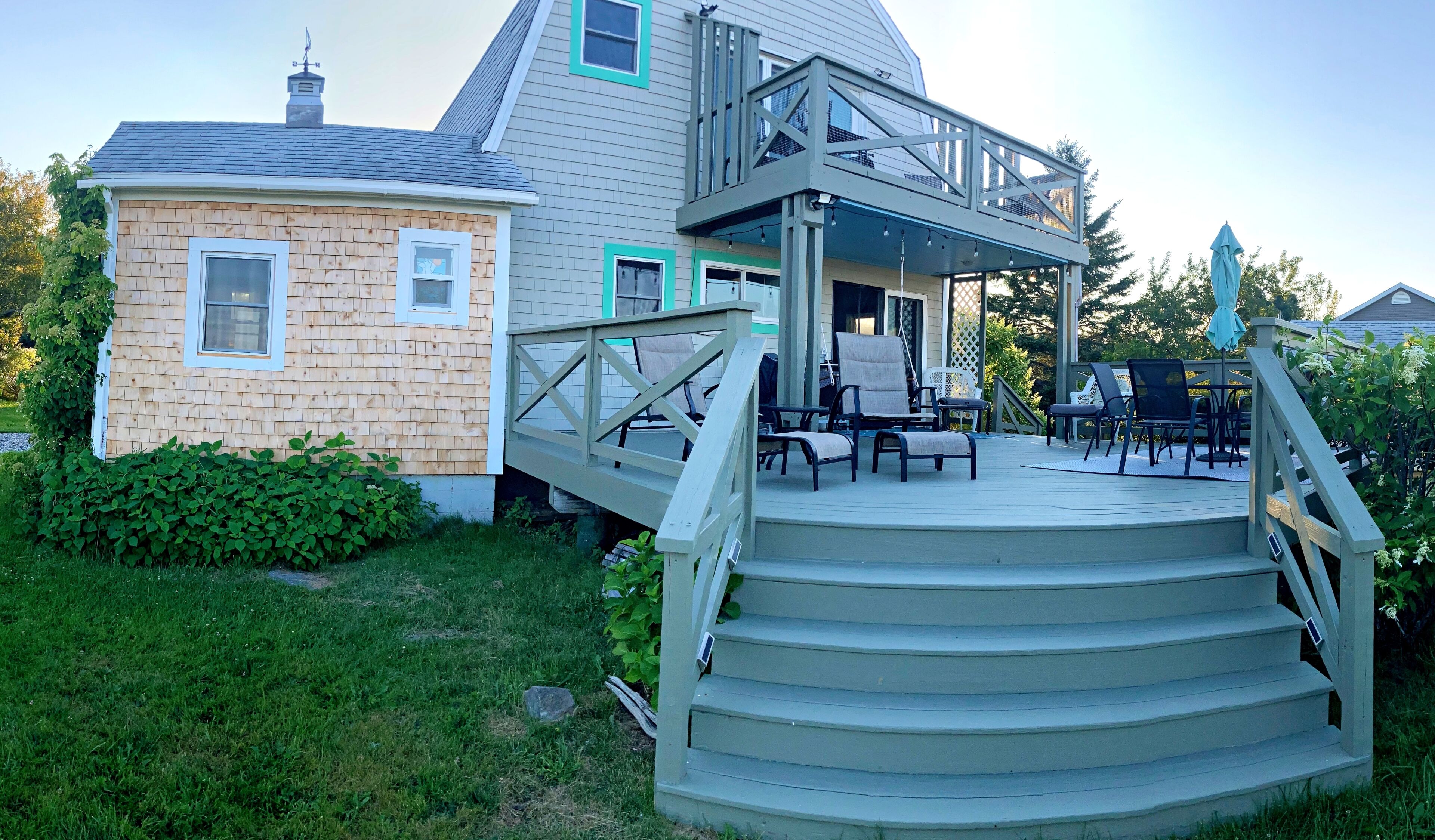 A two-story house with a wooden deck and outdoor seating area.