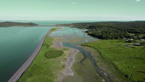 An aerial view of a coastal area with a long, narrow body of water, a winding river, and a forested area with scattered buildings. - Classic Maine Oceanfront Cottage, Gorgeous Views, Centrally Located, Pets, A/C (Lubec)