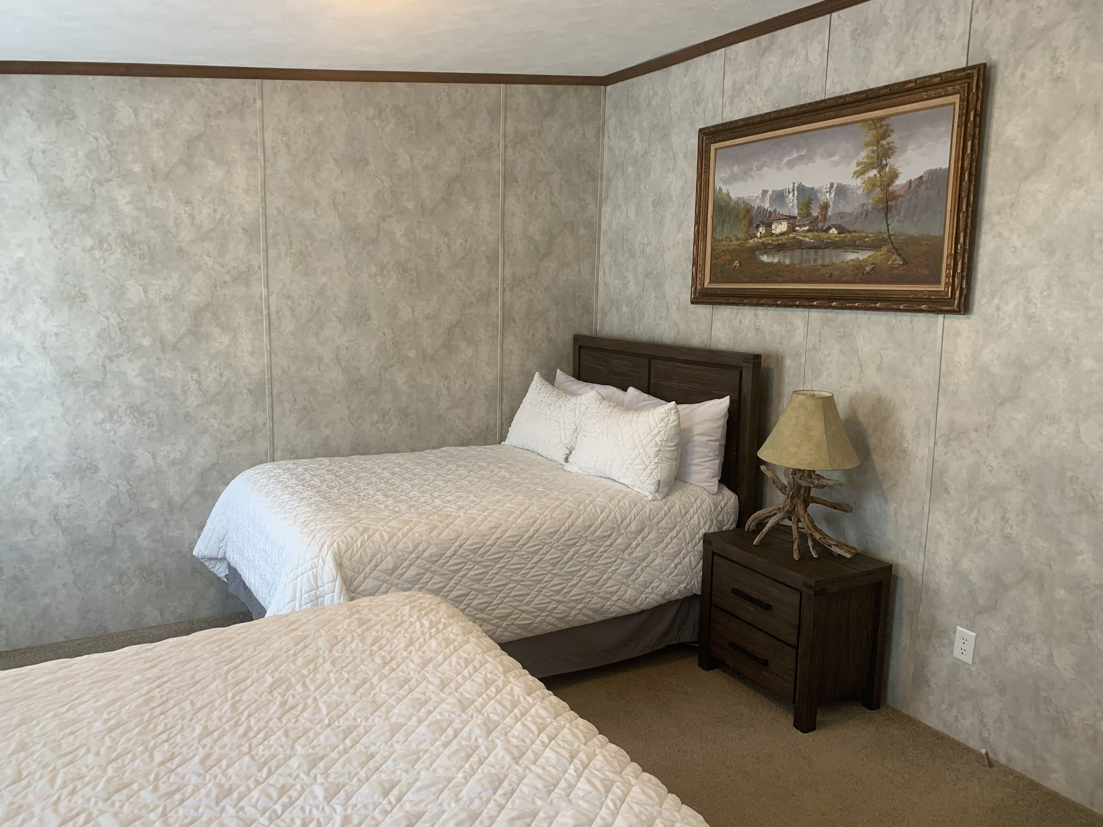 Een slaapkamer met een bed, nachtkastje en een schilderij aan de muur.