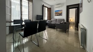 Un soggiorno moderno con zona pranzo, divano, televisione e un quadro appeso al muro.