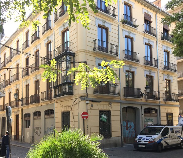 A multi-story building with balconies, a no-entry sign, and a parked van.