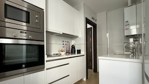 Una cucina moderna con elettrodomestici in acciaio inossidabile, mobili bianchi e un design pulito e minimalista.