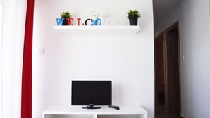 Un espace d’accueil moderne avec une console blanche, un téléviseur noir et une pancarte « BIENVENUE » placée au-dessus.