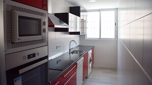 Une cuisine moderne dotée d’appareils électroménagers en acier inoxydable, d’un lave-vaisselle intégré et d’une fenêtre laissant entrer la lumière naturelle.