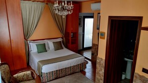 A bedroom with a bed, curtains, a chandelier, a wooden wardrobe, and a bathroom visible through an open door. - Venice Holiday Home, free wi-fi, private garden, romantic and affordable. (Mogliano Veneto)