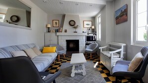 Una sala de estar con chimenea, un sofá, sillones, una mesa de centro y un radiador.