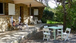 A stone building with a covered patio, outdoor seating, and a tree. - 400m from the beach, garden level with 1.250 m2 of enclosed land (Ramatuelle)