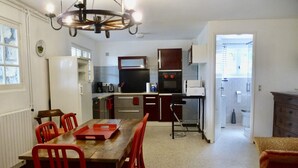 A compact kitchen with a dining area, a chandelier, and a view into the living room. - 400m from the beach, garden level with 1.250 m2 of enclosed land (Ramatuelle)