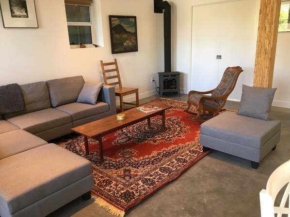Una sala de estar con un sofá modular, dos sillones, una mesa de centro, una alfombra estampada, una chimenea y obras de arte en las paredes.