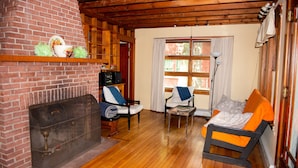 A cozy living room with a brick fireplace, wooden flooring, and two rocking chairs.