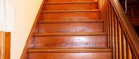 A wooden staircase with a handrail and a light fixture above.